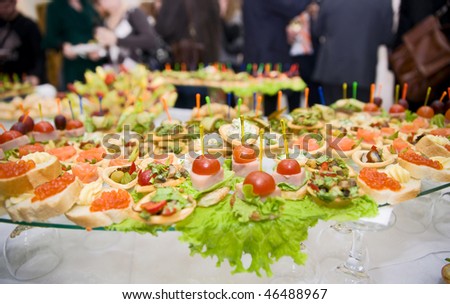 Full banquet table, unrecognizable eating people in blurred background