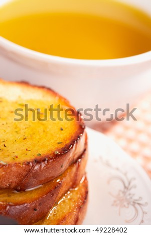Three pieces of toasted bread in olive oil, cup of oil in background, copy space