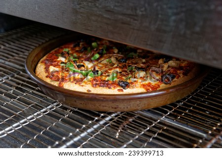 Pizza being baked in industrial oven, fast food restaurant