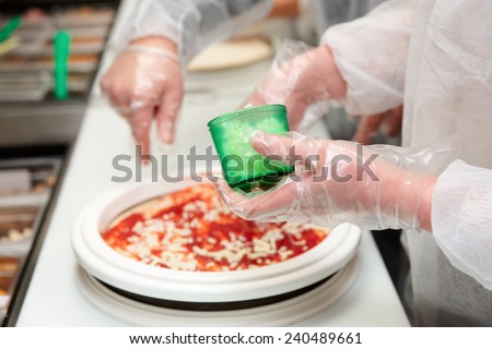Culinary student is cooking pizza, tutor\'s hand at the background