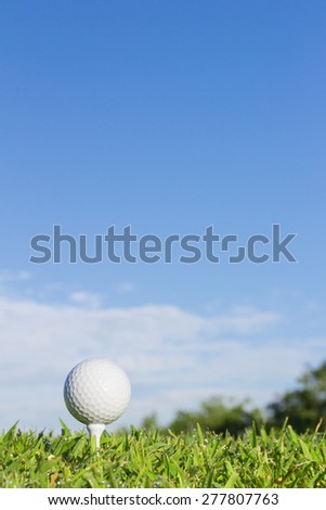 Golf ball on a tee with cloud and sky background