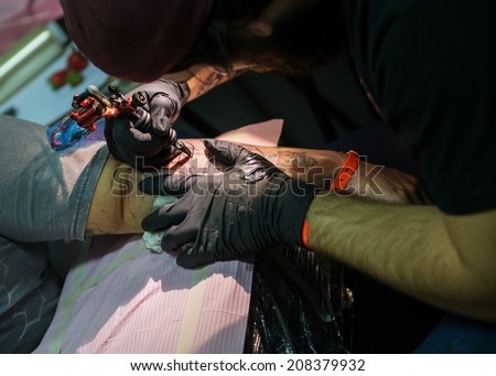 ROME - MAY 11: Tattoo artist draws with his tattoo machine on client\'s arm a new tattoo design in his workshop on May 11, 2014 in Rome