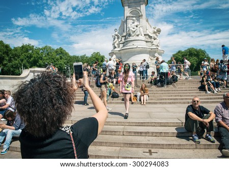 LONDON, UK - JULY 10: Tourist take a picture of friend near the Victoria Memorial, Buckingham Palace, London on 10 July 2015