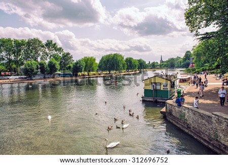 STRATFORD UPON AVON, UK - JULY 12: Family feeds swans and ducks, in the background boats with tourists on the river Avon on 12 July 2015