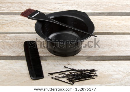 Hair color brush, and bowl with comb and pins on wooden surface