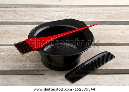 Hair color brush, and bowl with comb on wooden surface