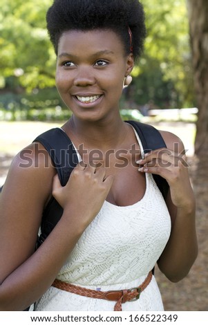 Beautiful black female holding back pack on her back smiling