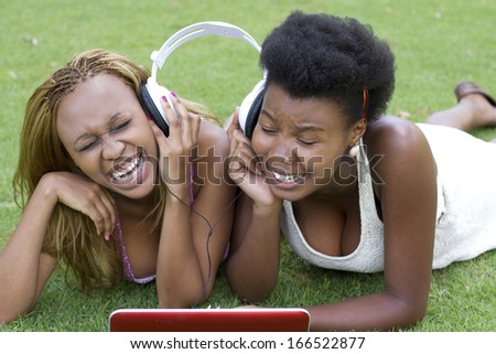 Beautiful black females sharing head phones enjoying themselves