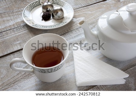 Red tea, teapot and tea ball infuser on table