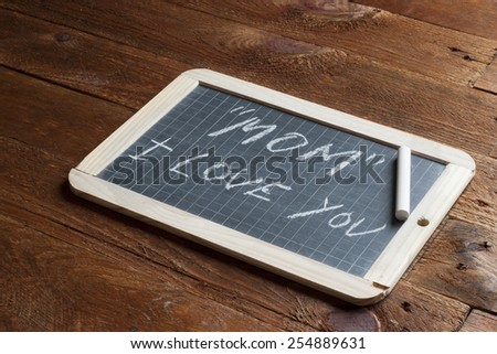 Mom I love you written on blackboard with frame and rustic wooden table