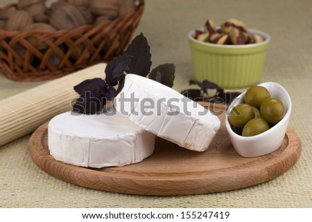 Cheese platter with nuts and grapes, olives and herbs on a wooden plate