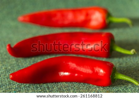 three red fresh pepper lie on a green mat