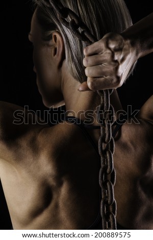 A woman with muscle definition holds a heavy chain.