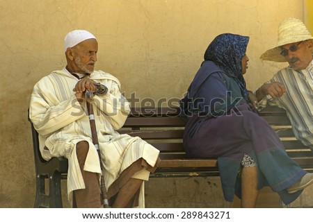 MARRAKESH, MOROCCO - APRIL 25: A stylish old Moroccan man in a long white gown seating in a bench in the street in Marrakesh, in Morocco, on April 25th, 2015
