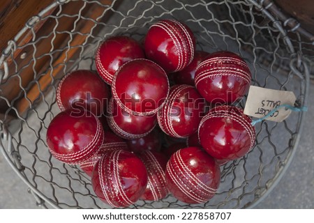 Close-up of shiny red real-leather cricket balls in a wire basket