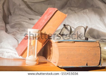 Antique book with eyeglass and hour glass