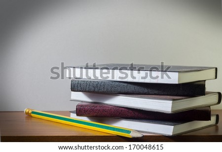 Stacked memory books with pencil.