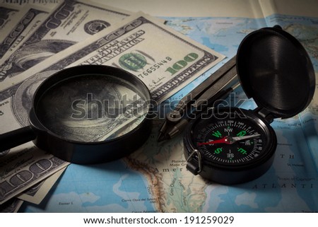Compass with magnifier and money on map,business concept.