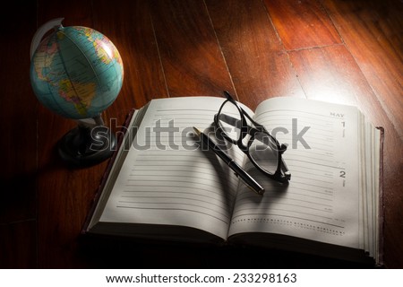 Globe with eyeglasses,pen and plan book