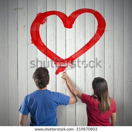 Young couple drawing a big red heart