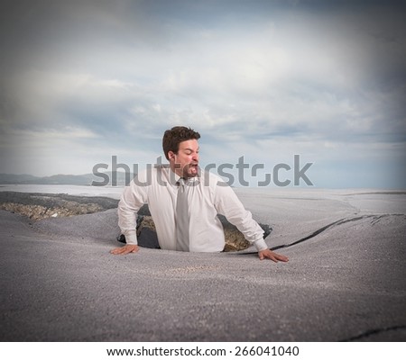 Businessman alone and afraid swallowed by asphalt
