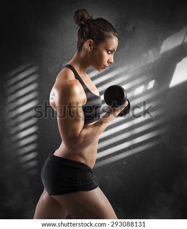Gym woman train her biceps with dumbbells