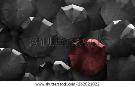 Stand out from the crowd. Red umbrella in mass of black