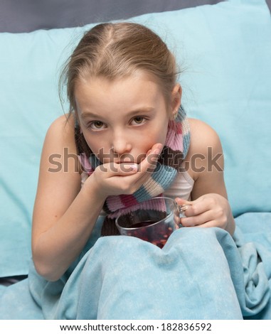 Sick child take medicine with a cup of herbal tea in hands