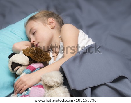 School age girl sleeps with his a favorite toy dog