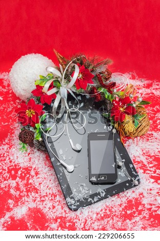 Tablet PC and cell phone black color best Christmas gifts on a red background decorated christmas flower.
