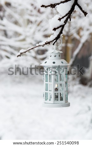 Burning lantern hanging on the branch snow winter day