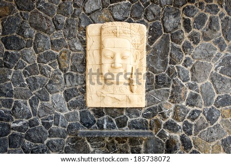 Face of sandstone carving hang on the stone wall