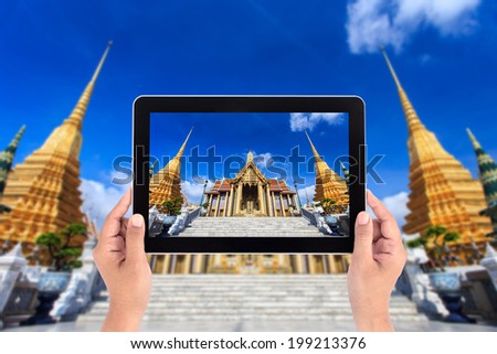 Hands holding tablet taking pictures at Wat Phra Kaew, Temple of the Emerald Buddha, Bangkok, Thailand.