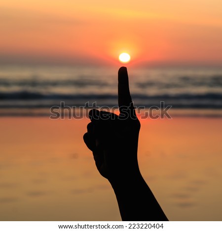 Silhouette of hands play with the sun at beach in sunset time