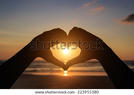 Silhouette of hands in heart  symbol around the sun