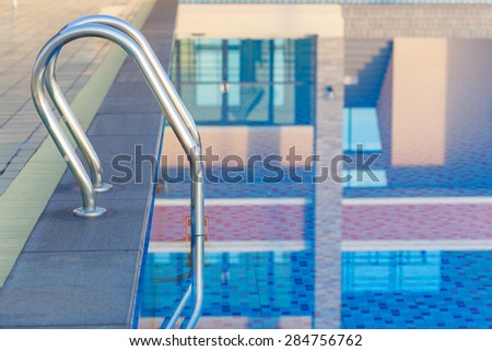 Close up stainless steel stair in swimming pool and water reflection