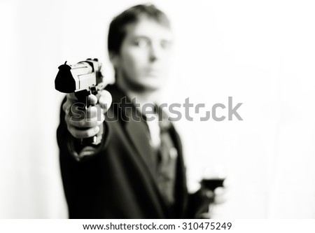 A guy with a gun in a suit holding a glass of wine