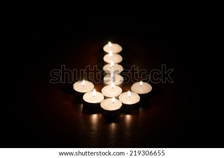Burning candles in the shape of an arrow on a black background
