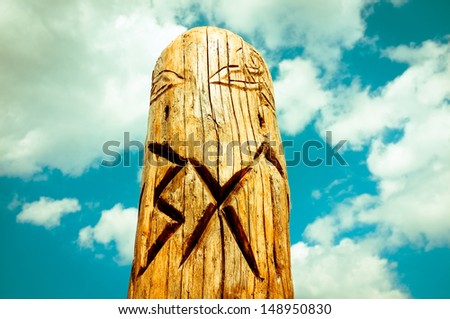 Picture of a slavic traditional totem pole at the background of a blue, cloudy sky, during summer sightseeing in Polish / Czech Republic Mountain Range of Karkonosze.