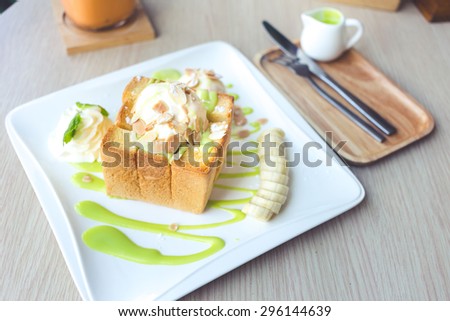 Ice cream on honey toast topped with Thai Pandan Custard on wooden table.