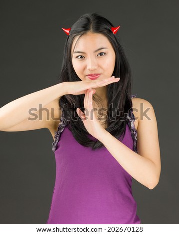 Devil side of a young Asian woman making time out signal with hands