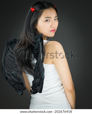 Rear view of a Upset Asian young woman dressed up as an devil turning back