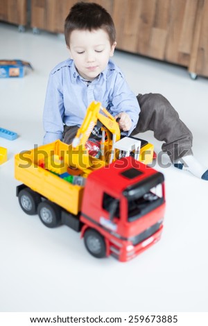 Cute boy playing with toy trucks at home