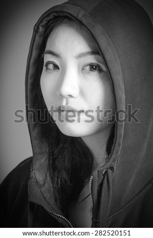 Attractive asian girl in her twenties isolated on a plain background, black and white image shot in a studio