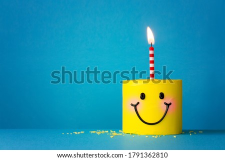 Yellow happy face birthday cake with one candle