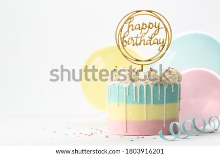 Pastel birthday cake with drip icing and balloons