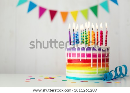 Rainbow birthday cake with colorful candles and drip icing