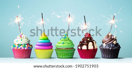 Assortment of brightly colored celebration cupcakes decorated with sparklers for a birthday party