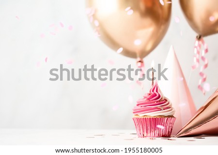 Birthday celebration with pink birthday cupcake, party hats and rose gold balloons