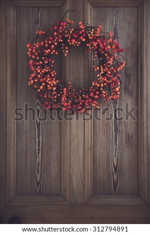 Fall berry wreath hanging on a wooden door